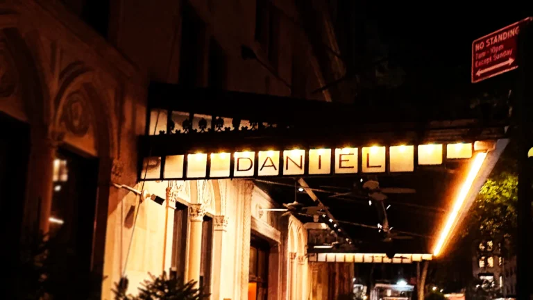 Entrance sign of Daniel restaurant in New York City, illuminated at night.