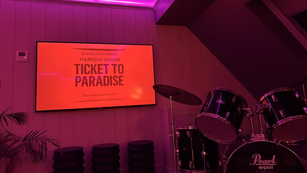 Drum set and movie screen in The Studio room at Dormy House with pink mood lighting