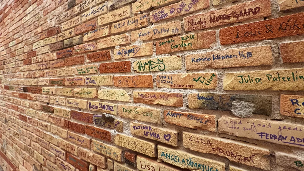 Brick wall at Noma restaurant in Copenhagen covered in handwritten names and messages from former staff and visitors