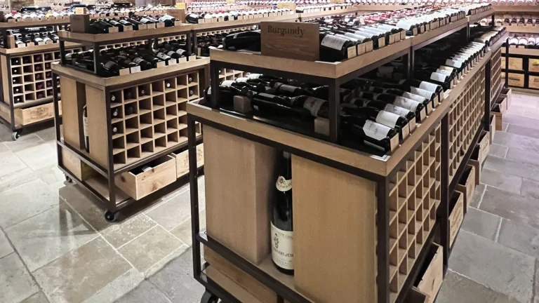 Wine storage racks filled with bottles in a cellar, featuring wooden cubby shelving units