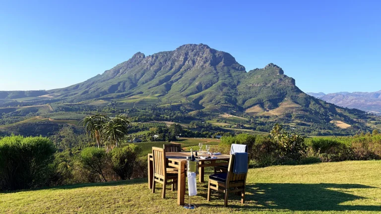Sundowner table set on a grass plateau overlooking Simonsberg mountain at Delaire Graff Estate